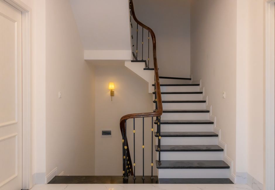Escalier tournant avec rampe en bois et balustrade en métal dans une maison